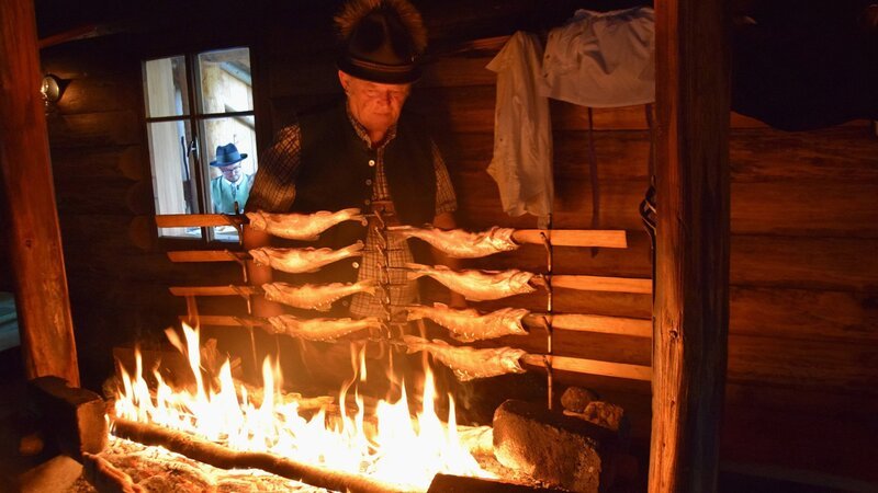 Zu Tisch Salzkammergut – Österreich Ein Mann grillt mehrere Seesaibling über offenem Feuer. – Bild: SRF/​Berlin Producers Media/​Gero von Marientreu