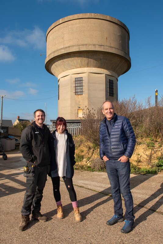 Adam (l.) mit Tassy (m.) und Kevin McCloud (r.) – Bild: RTL /​ Tippleston Photography /​ Familiendomizil im Turm
