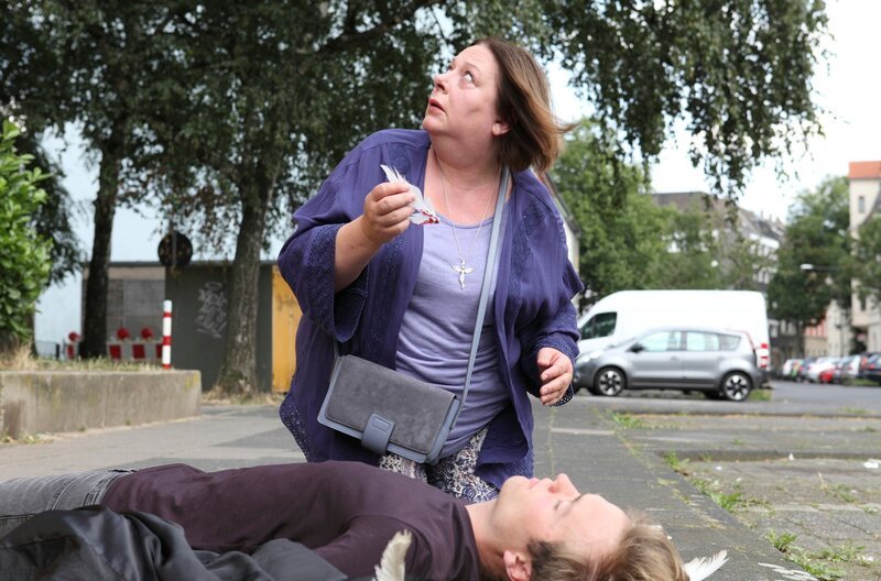 Gabriel Ruthe (Tristan Becker, vorne) fällt vom Dach eines Hochhauses. Unter seinem Rücken sind eindeutig Federn zu sehen, weshalb Maria Fröbel (Martina Eitner-Acheampong) ihn für ihren Schutzengel hält. – Bild: ARD/​Frank W. Hempel