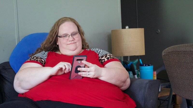 Delana sitting on the couch on her phone – Bild: Warner Bros. Discovery, Inc. or its subsidiaries and affiliates.