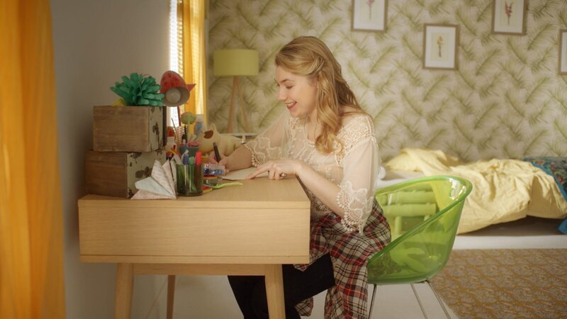 Claudine (Audrey Hall) ist begeistert vom Leben in der Gegenwart und schreibt dies Frank in einem Brief. Und sie berichtet ihm alles über Lena, so wie sie es versprochen hatte. – Bild: ZDF /​ Cottonwood Media /​ Opéra national de Paris /​ KiKA