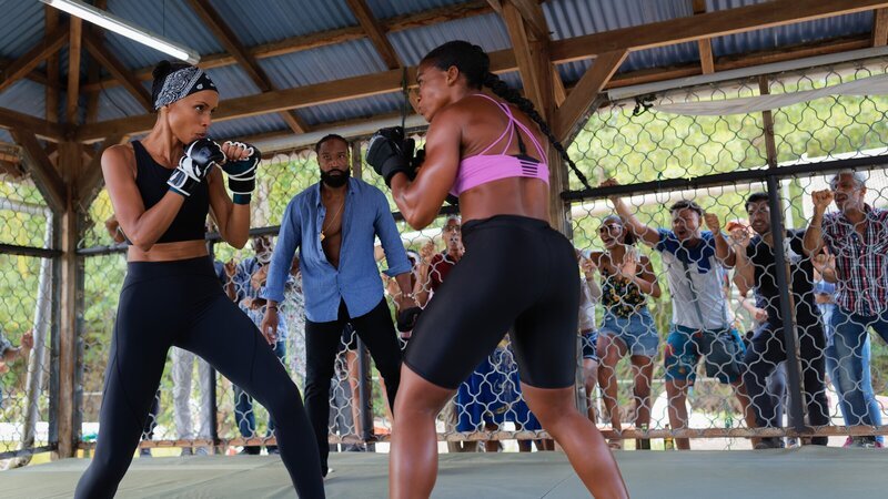 Mélissa (Sonia Rolland, l.) muss im Rahmen der Ermittlungen an einem illegalen Boxkampf teilnehmen. Unter Aufsicht des Schiedsrichters (Rodman, M.) hat sie gegen eine starke Gegnerin (Sephora Bissoly, r.) zu kämpfen. – Bild: ZDF