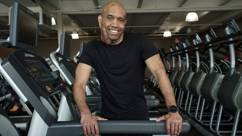 Marlow Williamson smiles for a picture as he places both hands on one side of the treadmill and slightly leans over. – Bild: TLC (FINN)