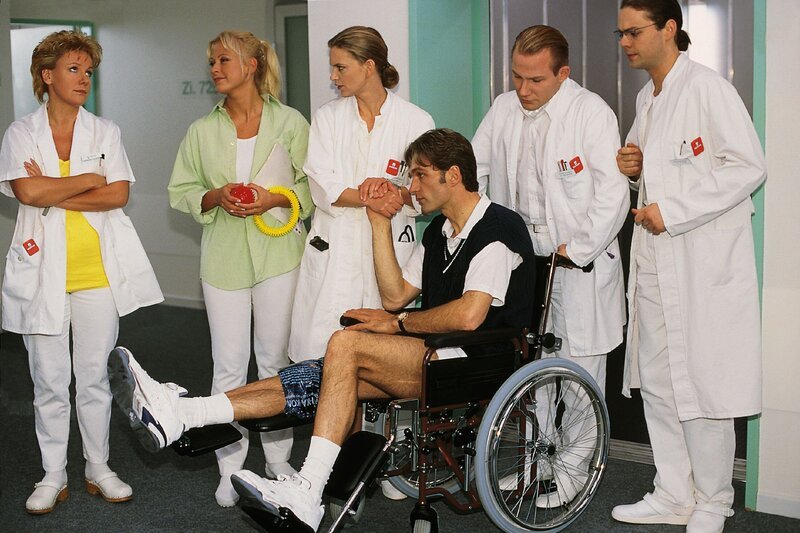 Dr. Schmidt (Walter Sittler, vorne), der sich beim Tennisspielen verletzt hat, hält seine Kollegen nun als Patient auf Trab (v.li.: Mariele Millowitsch, Jenny Elvers, Kerstin Thielemann, Roland Jankowsky, Alexander Schottky). – Bild: RTLplus