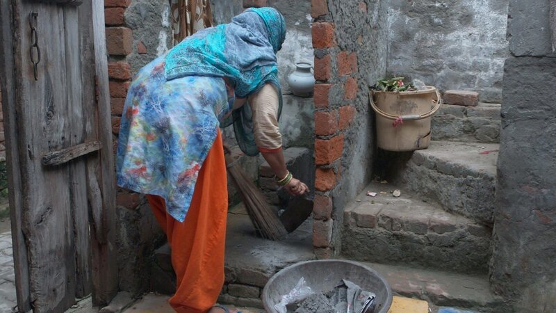 Eine Frau aus der Kaste der Dalit, die „Unberührbaren“, reinigt Latrinen von Fäkalien mit der Hand – laut Gesetz ist diese Art der Arbeit verboten. – Bild: ZDF und Deutsche Welle