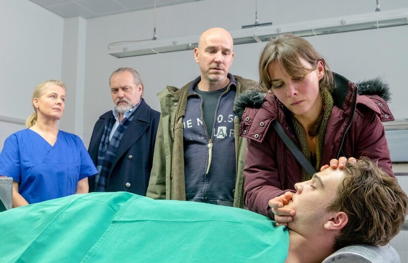 Im Beisein von Hauptkommissar Richard Voss (Jan-Gregor Kremp, 2.v.l.) und der Gerichtsmedizinerin Dr. Franziska Sommerfeld (Christina Rainer, l.) nehmen Bernd Rotthoff (Paul Herwig, 2.v.r.) und seine Frau Stefanie Rotthoff (Kathrin von Steinburg, r.) in der Rechtsmedizin Abschied von ihrem Sohn Maik Rotthoff (Manuel Kandler, vorne). – Bild: Erika Hauri /​ ORF /​ ZDF