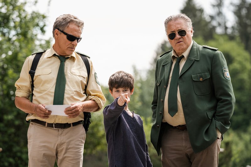 Franz Hubert (Christian Tramitz) und Reimund Girwidz (Michael Brandner) sprechen mit einem Jungen – Bild: Leonine /​ Leonine Licensing GmbH /​ Entertainment Factory Film- und Fernsehproduktions GmbH