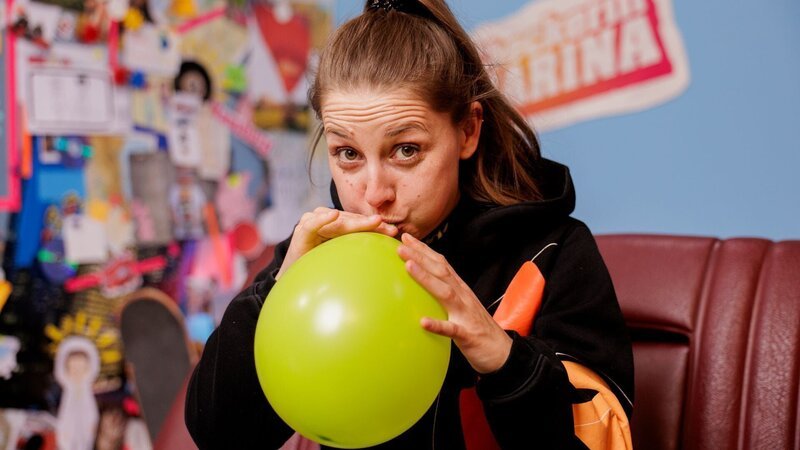 Marina checkt, wie viele Atemzüge sie benötigt, um einen Luftballon aufzupusten. – Bild: BR/​megaherz gmbh/​Hans-Florian Hopfner