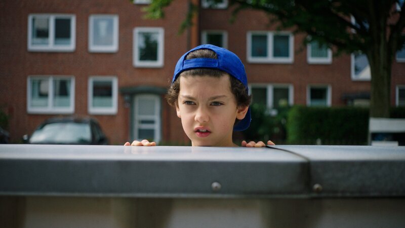 Piet (Noah Lusander) beobachtet die Tankstelle aus sicherer Entfernung. – Bild: NDR/​Letterbox