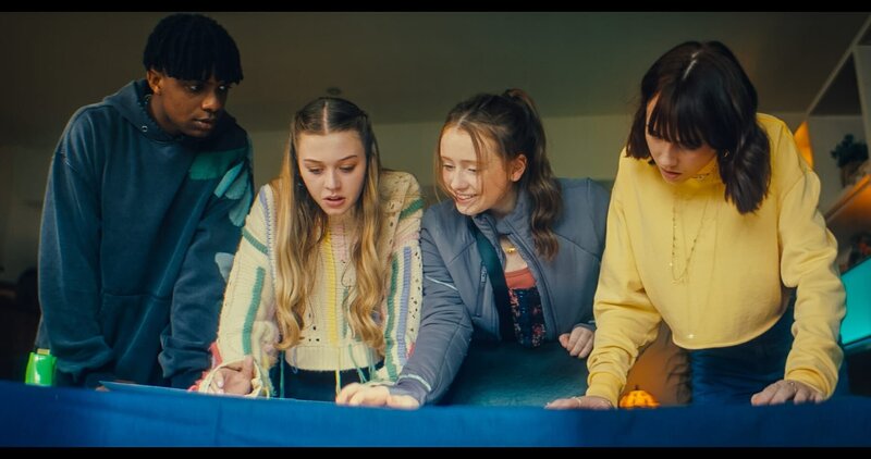 In der Wohnung von Alices Mutter betrachten Finn (Jordan Adene), Maeve (Skye McClenaghan), Bea (Aoife Hughes) und Alice (Scarlett Rayner, v.l.n.r.) die Ausdrucke der Fotos, die sie von der aufgemalten Wegbeschreibung auf Maeves Arm gemacht haben. Bea weiß, wo sie die Suche nach ihren Freunden starten müssen. – Bild: ZDF/​Zodiak Kids & Family Productions UK Ltd.