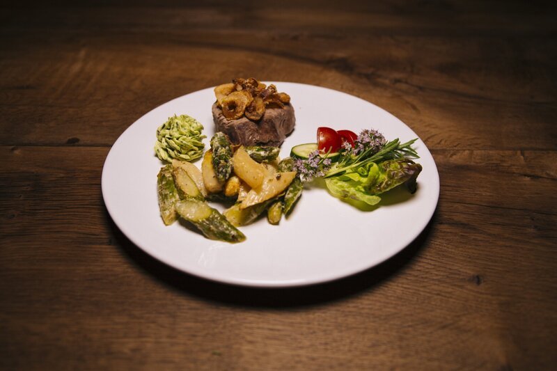 Die Hauptspeise: Holzfällersteak mit Zwiebelringen und selbstgemachter Kräuterbutter, dazu gebratener Spargel und frischer Salat. – Bild: BR/​megaherz gmbh/​Andreas Maluche