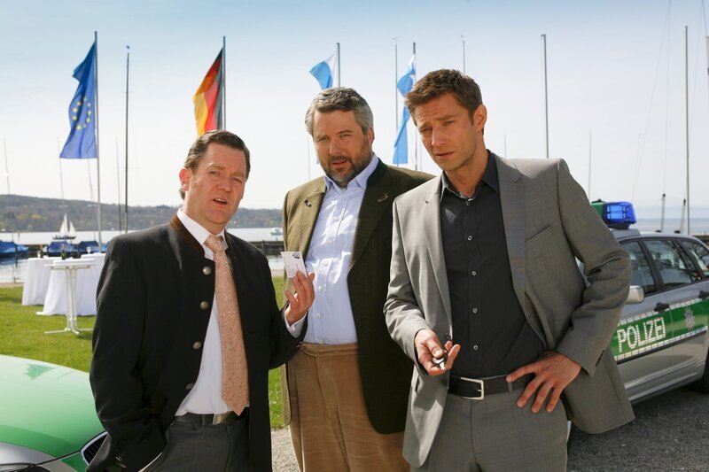 Im Yachthafen stellen die Cops Stadler (Dieter Fischer, M.) und Hansen (Igor Jeftic, r.) Bürgermeister Schretzmayer (Jürgen Tonkel, l.) zur Rede. – Bild: ZDF und Christian A. Rieger