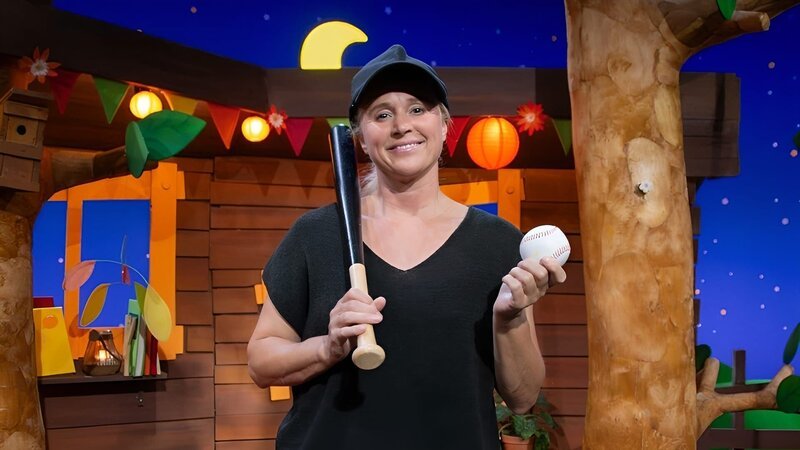 Singa erzählt von dem Sport Baseball. Ihr wurde ein Video geschickt, in dem ihr gezeigt wird, wie man mit dem Ball und Schläger spielt. – Bild: KiKA