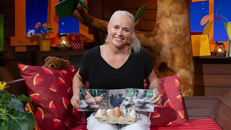 Singa bekommt ein Video, in dem ihr Hühner gezeigt werden. Sie erklärt, wie man erkennen kann, welches Ei von welchem Huhn gelegt wurde. – Bild: KiKA /​ KiKA