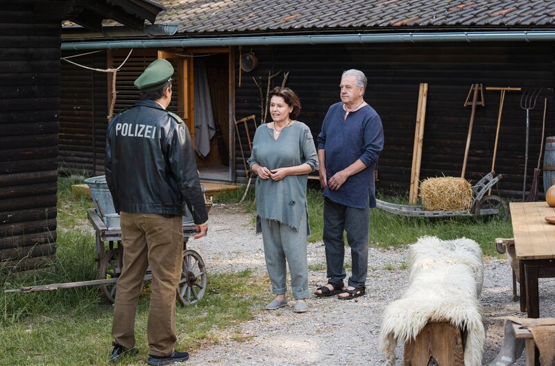 Riedl (Paul Sedlmeir, l.) entdeckt auf dem Gutshof seine Eltern (Pia Hänggi, M. mit Komparse) und ist überrascht. – Bild: ARD/​Max Bublak /​ ARD-Programmdirektion