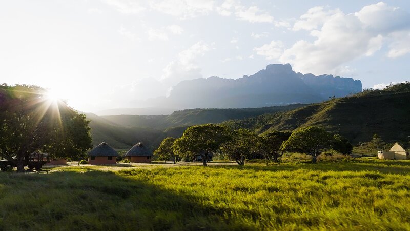 Fast 2500 Meter hoch ragt der Auyan-Tepui über der Savanne im Süden Venezuelas auf: Von seinen Steilwänden stürzt unter anderem der höchste Wasserfall der Welt in die Tiefe – der Salto Ángel. In der Siedlung Kavak, am Fuß des Tepuis, entsteht das Basislager der Expedition. – Bild: Hans Hornberger /​ ZDF