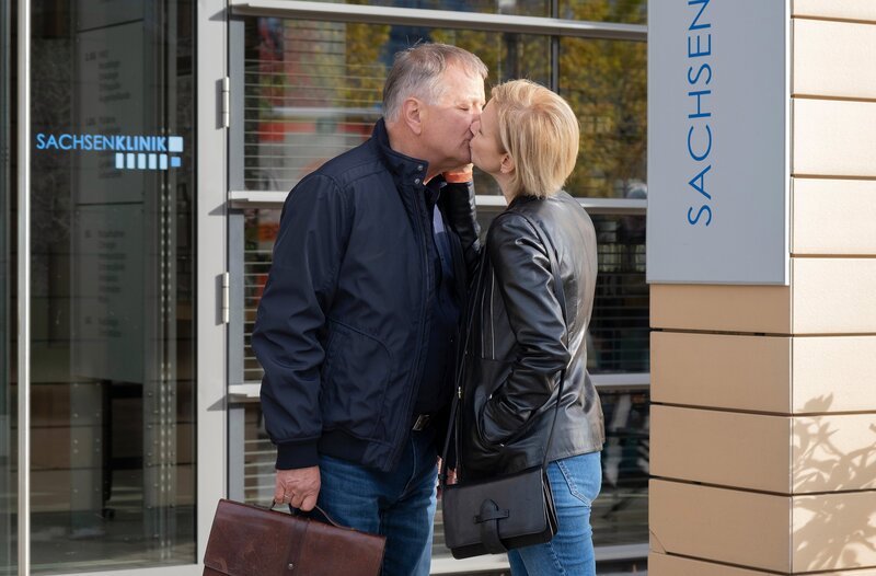 Bea Hölsch (Daniela Wutte, re.) ist mit Fieber umgekippt und hat sich einen Schlüsselbeinbruch zugezogen. Ihren behandelnden Arzt Dr. Martin Stein (Bernhard Bettermann, li.) bringt sie mit ihrem sehr anschmachtenden Verhalten in eine ziemlich unangenehme Situation. Auch Dr. Kathrin Globisch (Andrea Kathrin Loewig, mi.) ist ziemlich irritiert. – Bild: MDR/​Saxonia Media/​Sebastian Kiss