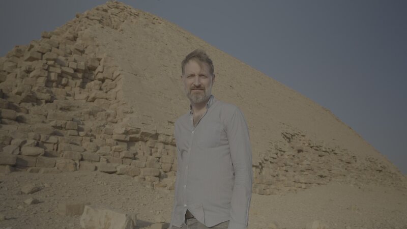 Der Ägyptologe Chris Naunton steht vor der Knickpyramide. – Bild: Windfall Films/​Celestine Fünfgeld