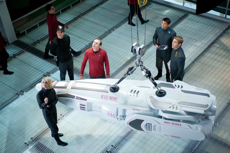Nach dem Anschlag von John Harrison sollen Captain Kirk (Chris Pine, r.), Dr. Leonard ‚Pille‘ McCoy (Karl Urban, 2.v.r.), ‚Scotty‘ Scott (Simon Pegg, 3.v.r.) und Carol (Alice Eve, l.) bis zum Rand der „neutralen Zone“ vordringen und von dort aus den Attentäter mit neuartigen Langstrecken-Photonentorpedos beschießen. Doch kann die Besatzung der Enterprise Admiral Marcus’ Anweisungen trauen? – Bild: Paramount Pictures