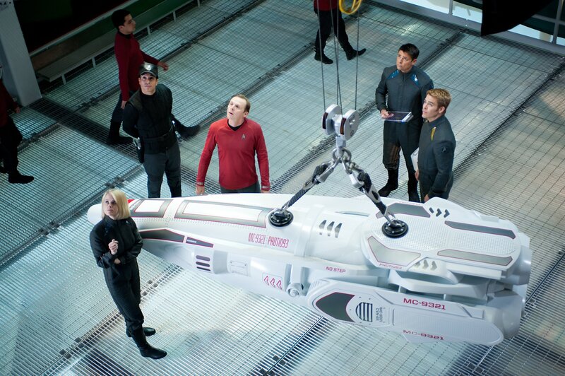 Nach dem Anschlag von John Harrison sollen Captain Kirk (Chris Pine, r.), Dr. Leonard ‚Pille‘ McCoy (Karl Urban, 2.v.r.), ‚Scotty‘ Scott (Simon Pegg, 3.v.r.) und Carol (Alice Eve, l.) bis zum Rand der „neutralen Zone“ vordringen und von dort aus den Attentäter mit neuartigen Langstrecken-Photonentorpedos beschießen. Doch kann die Besatzung der Enterprise Admiral Marcus’ Anweisungen trauen? – Bild: Paramount Pictures
