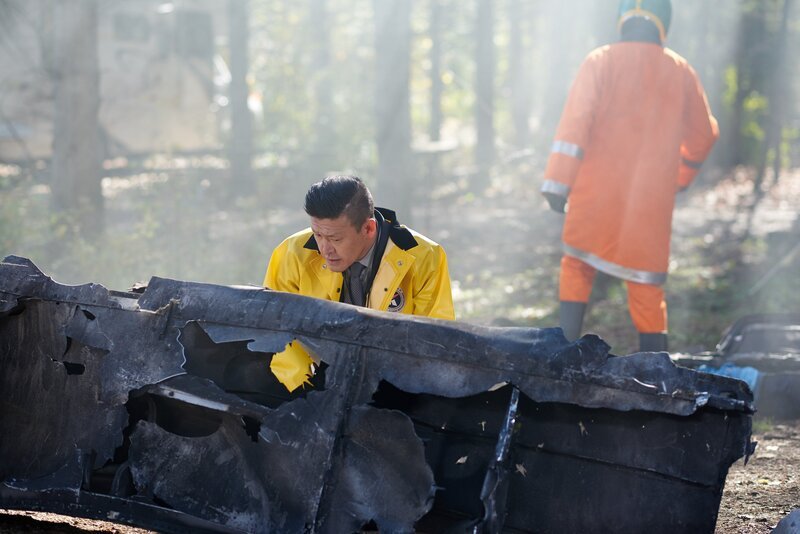 Ein KAIB-Ermittler (gespielt von Daniel Park) untersucht das Wrack von Flug 129 der Air China. – Bild: Cineflix/​Steven Lungley