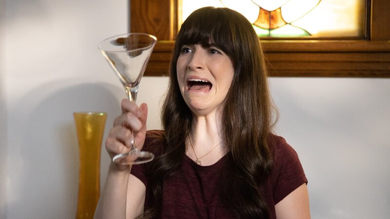 Die Frau schaut ängstlich auf das Glas. – Bild: Warner Bros. Discovery