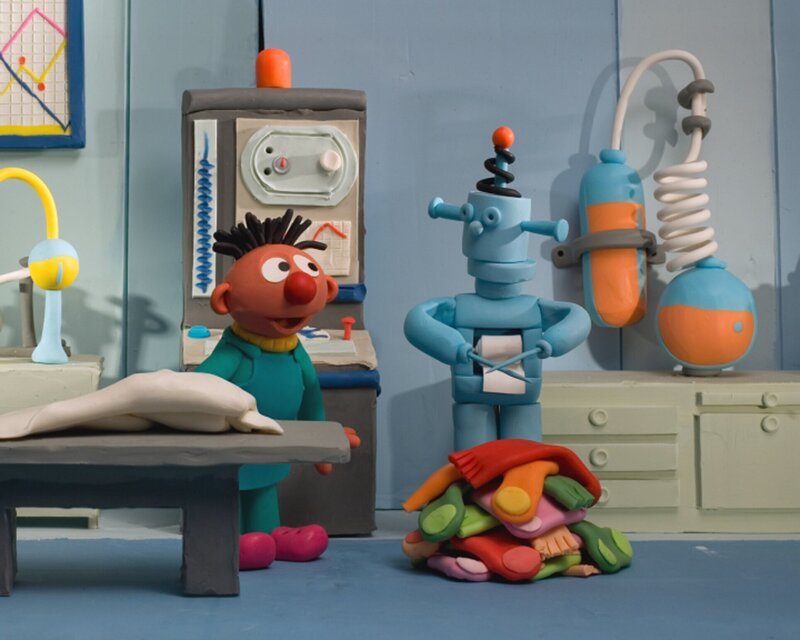 Ernie wundert sich über den Roboter, der sogar Socken stricken kann. – Bild: NDR/​Sesameworkshop