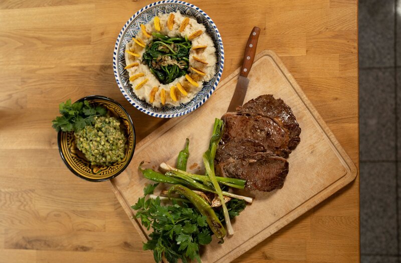 Das Hauptgericht von Profikoch Ali Güngörmüs: Steak mit Ayamashe, Fufu, Spinat und Bananenchips. – Bild: HR/​Sabine Brox
