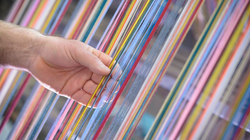 Worker adjusting multicoloured silk yarn on industrial loom in textile mill – Bild: Discovery