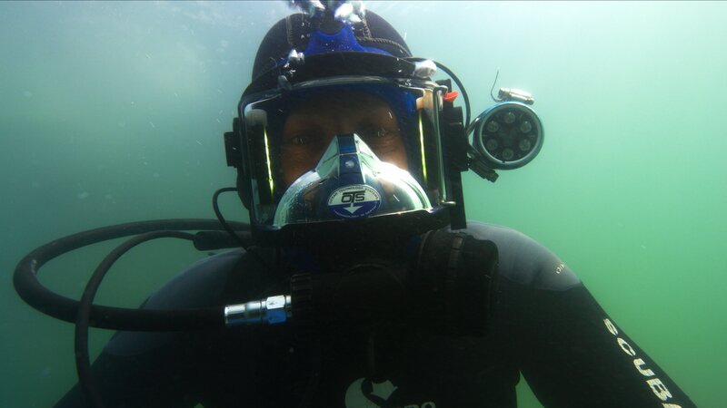 Kris Kelly looks at the camera underwater as he goes down for a dive. – Bild: Discovery Communications, LLC