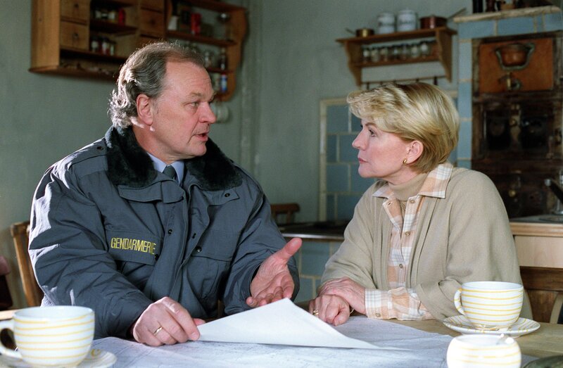 Der Gendarm Heinz Strubreiter (Michael König) erklärt Julia (Christiane Hörbiger) die Lage. – Bild: ORF III