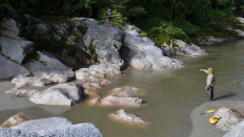 Cody Lundin and Joe Teti standing on rocky river bank. – Bild: Warner Bros. Discovery