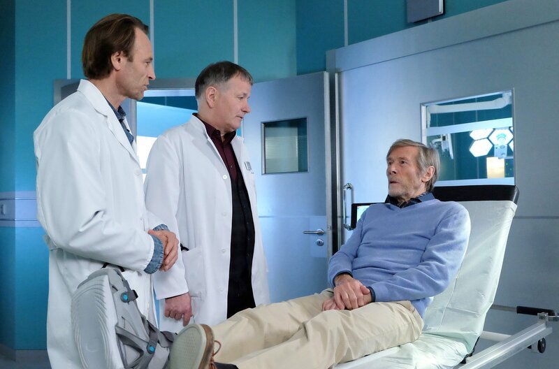 Dr. Henrik Oswald (Horst Janson, re.) der am Morgen für eine Beratertätigkeit in der Sachsenklinik war, wurde nun nach einem Autounfall mit einem gebrochenen Fuß eingeliefert. Als Dr. Roland Heilmann (Thomas Rühmann, mi.) und Dr. Martin Stein (Bernhard Bettermann, li.) nach dem genauen Unfallhergang fragen, fühlt Oswald sich sofort angegriffen: Er gehöre nicht zu den alten Menschen, die im Straßenverkehr mit zunehmendem Alter zur Gefahr werden. – Bild: MDR/​Saxonia Media Filmproduktion /​ MDR/​HA Kommunikation