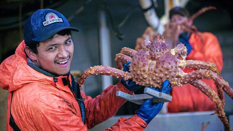 Ein Mitglied der „Wizard“-Crew hält eine große Krabbe. – Bild: Discovery, Inc.