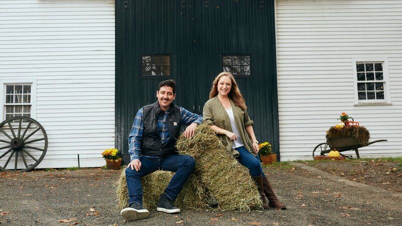 As seen on HGTV’s Farmhouse Fixer, Jonathan Knight, left, and his designer Kristina Cretin, work to revitalize farmhouses in the northeast. They are sitting in front of the barn on a property in Ipswich, Massachusetts. – Bild: Discovery Communications/​Stephanie Diani