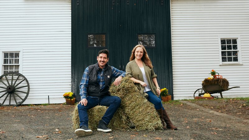 As seen on HGTV’s Farmhouse Fixer, Jonathan Knight, left, and his designer Kristina Cretin, work to revitalize farmhouses in the northeast. They are sitting in front of the barn on a property in Ipswich, Massachusetts. – Bild: Discovery Communications/​Stephanie Diani