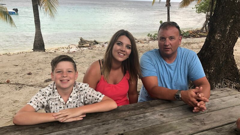 Clients Ryan Bilyk & Sarah Tofflemire pose with their son Chris on the beach in Utila, Honduras. As seen on HGTV’s Caribbean Life. – Bild: HGTV /​ Scripps (Focus) HCBLF1305_310093 /​ Scripps Networks, LLC. All Rights Reserved.