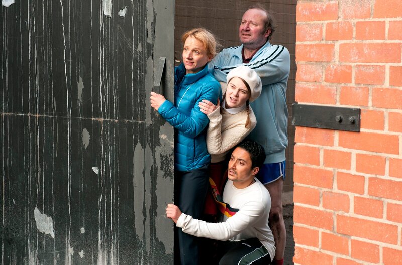 Da Titus auf eine Mine getreten ist, verstecken sich die anderen Mitarbeiter hinter dem Eingangstor des Sprach- und Kulturinstitutes. Von oben: Gmeiner (Rainer Reiners), Dr. Eckart (Christina Grosse), Jördis (Nadja Bobyleva) und Haschim (Omar El-Saeidi). – Bild: BR/​WDR/​NDR/​Novafilm