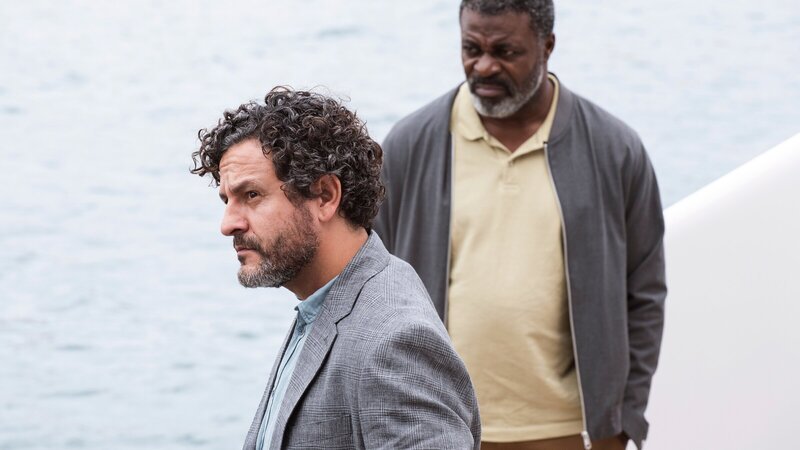 Inspector Castells (Isak Férriz, l.) zeigt Colin Sutherland (Danny Sapani) im Hafen von Barcelona die Yacht, auf der Colins Sohn Jay kurz vor seinem Tod als Barmanager gearbeitet hat. – Bild: ZDF