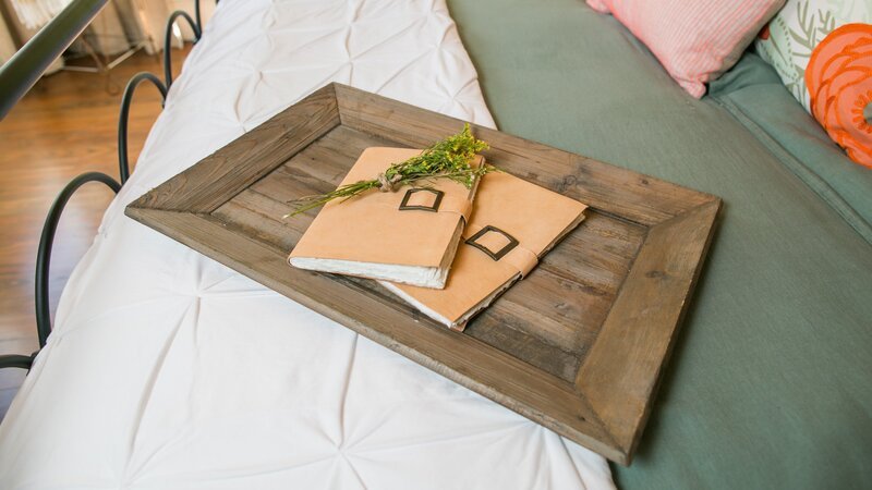 A close up of the wooden tray and journals on the bed in the master bedroom of the newly renovated Childers home, as seen on Fixer Upper. (after) – Bild: Rachel Whyte /​ HGTV /​ Scripps