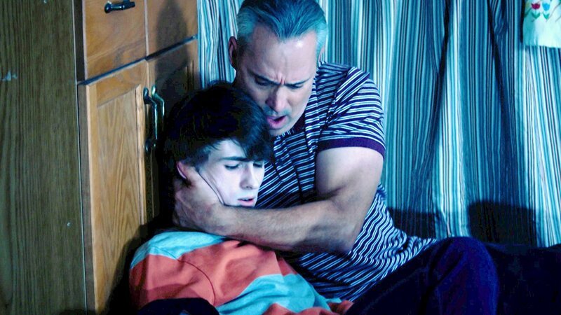 Ein Mann hält einen Jungen, während sie auf dem Boden sitzen – Bild: Crime + Investigation /​ Blackwatch