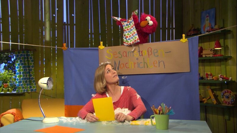 Elmo (oben) lässt es über Julia (unten) schneien. – Bild: NDR/​Sesame workshop