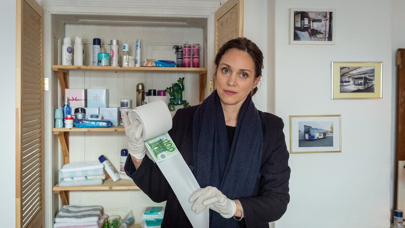 Kommissarin Karoline Joost (Nike Fuhrmann) staunt nicht schlecht. Im Bad der toten Beate Steinmann findet sie lauter Klopapierrollen, in die Geldscheine eingewickelt sind. Offenbar hat die Tote so ihr gesamtes Erspartes aufbewahrt. – Bild: ZDF und Marc Meyerbröker