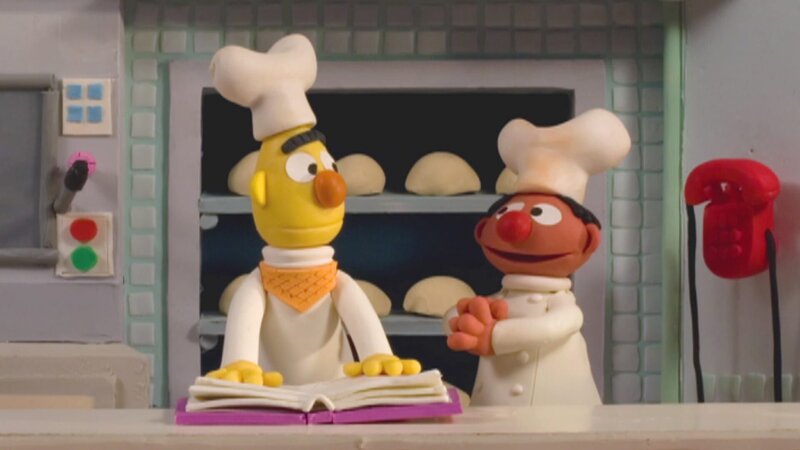 Ernie und Bert arbeiten als Bäcker in ihrer neu eröffneten Backstube. – Bild: NDR/​Sesameworkshop