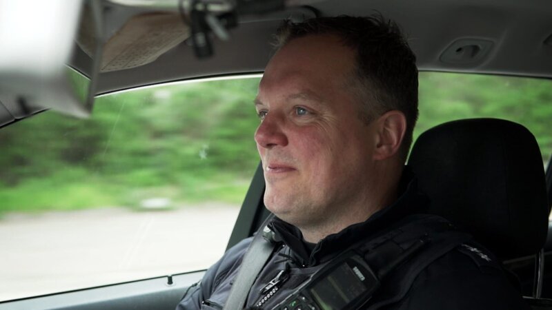 Ein lächelnder Mann in einem Auto – Bild: Warner Bros. Discovery