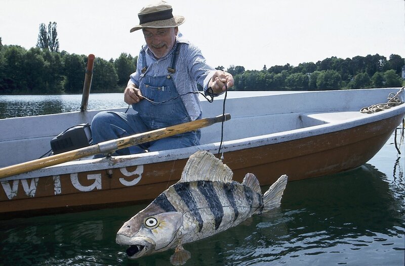 Peter (Peter Lustig) hat sich einen großen Fisch gebastelt. Im Inneren des Fisches steckt eine Kamera. Peter wird den Fisch schwimmen lassen, vielleicht erhält er so Fotos von dem Bärstädter See-Monster. – Bild: ZDF und Christiane Pausch