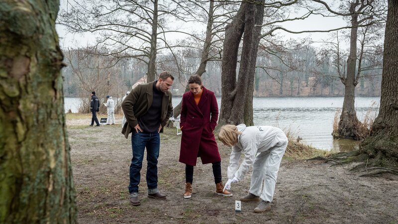 Kriminaltechnikerin Roswitha Prinzler (Silke Matthias, r.) zeigt Karoline Joost (Nike Fuhrmann, M.) und Lars Pöhlmann (Dominic Boeer, l.) Spuren von Patronenhülsen am Tatort. Der Täter hat zwei Mal auf den Toten geschossen. Für die Kommissare ist klar, was das bedeutet: Der Täter hat Daniel Kahlke unbedingt töten wollen. Doch warum musste der Hundezüchter sterben? – Bild: Marc Meyerbröker /​ ZDF