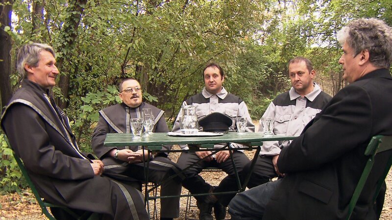 Regisseur Martin Polasek im Gespräch mit den „Pompfüneberern“, die nur in Uniform ernst sind und Wasser trinken. – Bild: ZDF/​ORF/​regie.tv/​Martin Polasek