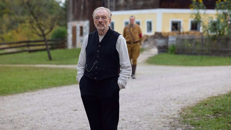 Der Schuster Julius Kraus (Josef Hader, l.) steht nachdenklich vor dem Heingeiger Hof, als Silvan (Sigi Zimmerschied, r.) zu ihm kommt. – Bild: ZDF und Mathias Bothor