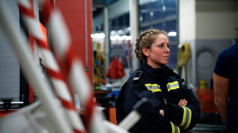 Ein eigentlich schon gelöschter Brand entpuppt sich als unübersichtliche Gefahrenquelle. Aus einem heruntergebrannten Einfamilienhaus am Stadtrand von Berlin steigt wieder Rauch auf. Mit Hilfe einer Wärmebildkamera wird der Einsatzort nach weiteren Glutnestern abgesucht. Auch die Nachtschicht in der Leitstelle hat am Wochenende mit besonderen Herausforderungen zu kämpfen. – Ausbilderin Sabrina in der Lehrfeuerwache Suarez. – Bild: rbb/​Klara Lübbe